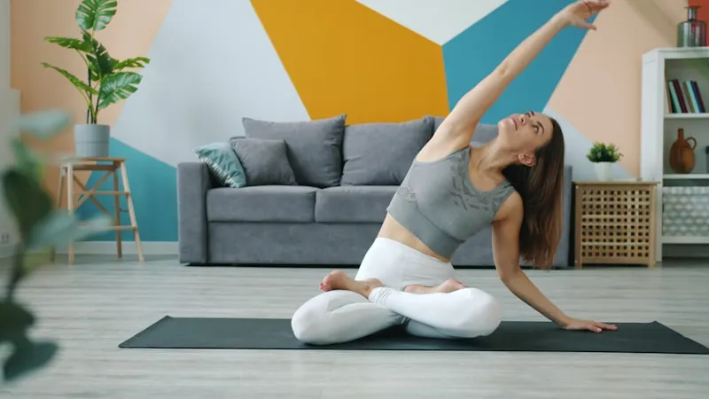 Woman practicing yoga on a mat in a living room.